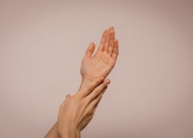 Close-up of hands gently caressing each other, symbolizing self-care and softness.